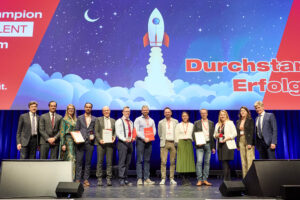 Menschen auf der Bühne halten ihren Preis und ihre Urkunden in der Hand